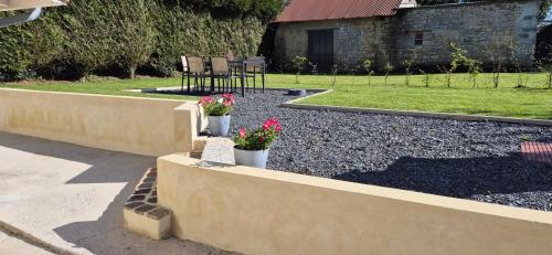 un jardin avec deux plantes en pot sur un mur de soutènement dans l'établissement Gite au cœur du dday, à Carentan