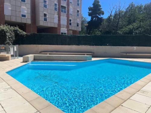 une piscine bleue en face d'un bâtiment dans l'établissement Résidence Balcon Du Canigou - T3 dans la résidence Les Balcons du Canigou MAE-4681, à Vernet-les-Bains