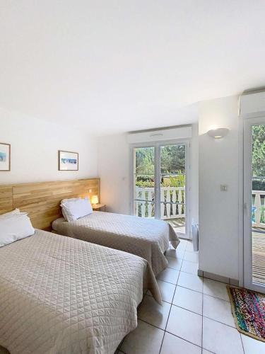 une chambre d'hôtel avec deux lits et un balcon dans l'établissement Résidence Atlantic Green - Villa spacieuse avec piscine chauffée pour 6 personnes Lacanau Océan MAE-1011, à Lacanau