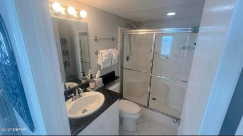 a bathroom with a shower and a sink and a toilet at Oceanfront Corner Unit with spectacular views in Ormond Beach