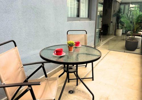 a glass table with two cups and two chairs at BHomy Oscar Freire 2 in Sao Paulo