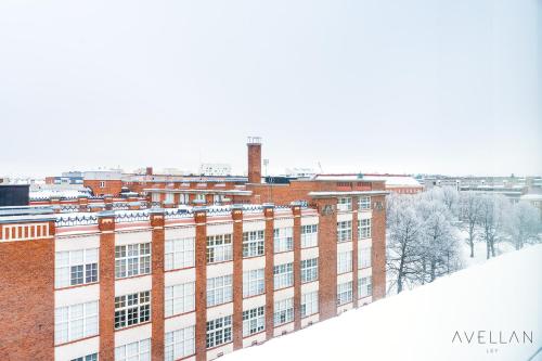 a large brick building with snow on the roof at Come in! "Ilmatar" Luxury apartments in the heart of Tampere with yacuzzi option! in Tampere