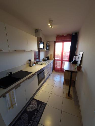 une cuisine avec des armoires blanches, une table et une fenêtre dans l'établissement Grand T1 Lumineux & Joli Balcon, à Marseille