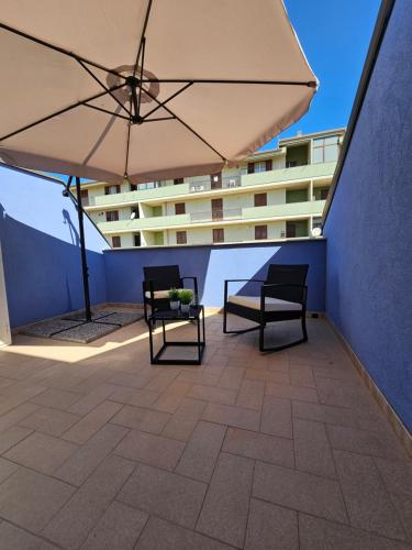 a patio with two chairs and an umbrella and a building at Aura B&B in Pachino