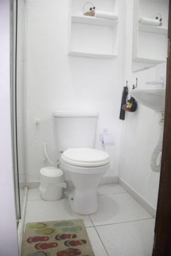 a white bathroom with a toilet and a shower at Pousada Cantinho de Minas Da Tânia in Cabo Frio