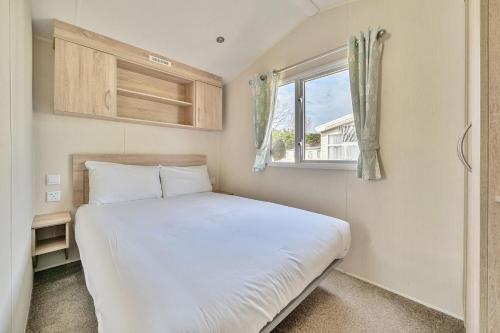 a small bedroom with a white bed and a window at Golden Dune - Hayling Island in South Hayling