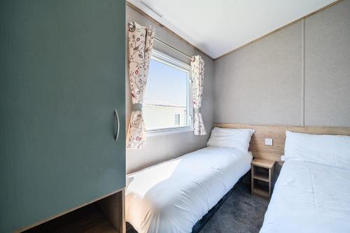 a small room with two beds and a window at Sunset Sands - Hayling Island in South Hayling