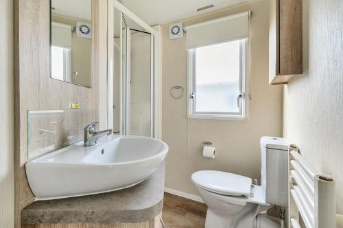 a white bathroom with a sink and a toilet at The Lookout - Hayling Island in South Hayling