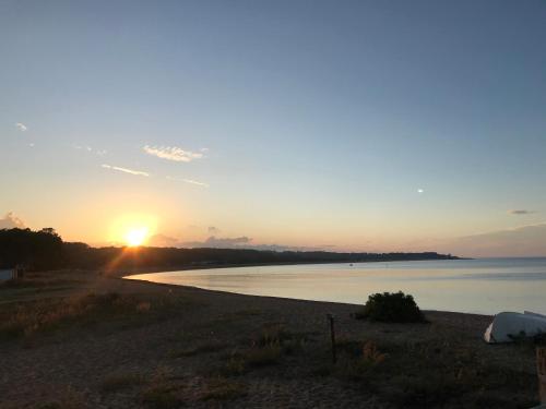 a sunset on a beach with the sun setting at Simrishamn, Österlen - privat boende med egen ingång in Simrishamn