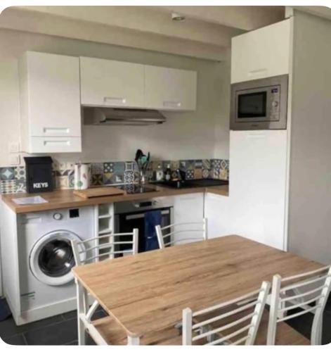 une cuisine avec une table et une machine à laver dans l'établissement Maison dans les dunes, à Le Touquet-Paris-Plage