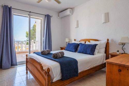 sypialnia z łóżkiem z niebieskimi poduszkami i oknem w obiekcie Villa Moggalatto by Villa Plus w mieście Calpe