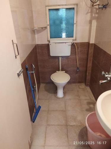 a small bathroom with a toilet and a window at Independent Bungalow with Private Garden in Thane