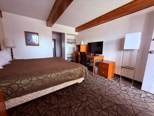 a hotel room with a bed and a desk at Tomahawk Motor Lodge By OYO Riverton US-26 in Riverton