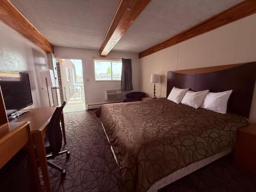 a hotel room with a bed and a desk and a television at Tomahawk Motor Lodge By OYO Riverton US-26 in Riverton