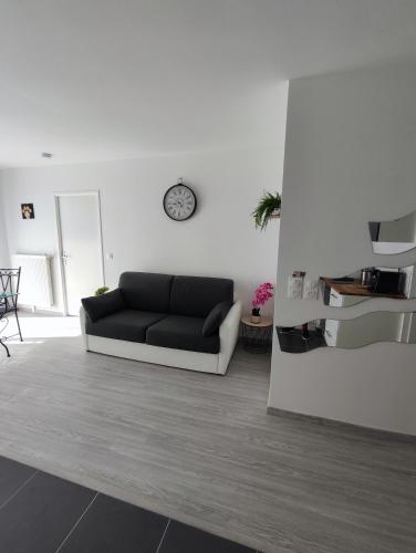 un salon avec un canapé et une horloge au mur dans l'établissement Joli appartement DISNEY Paris, à Bussy-Saint-Georges
