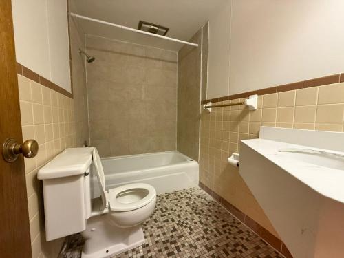 a bathroom with a toilet and a tub and a sink at Tomahawk Motor Lodge By OYO Riverton US-26 in Riverton