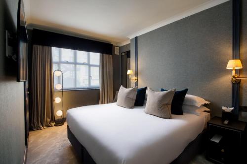 a large white bed in a hotel room with a window at The Capital Hotel, Apartments & Townhouse - Small Luxury Hotels of The World in London