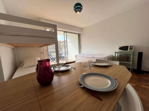 une pièce avec une table en bois avec des assiettes et des verres à vin dans l'établissement Résidence Le Vidourle - Studio 4 couchages au centre du Grau du Roi MAE-0973, au Grau-du-Roi