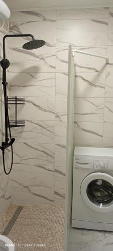 a washing machine in a bathroom with a wall at A cosy apartment near the border in Narva