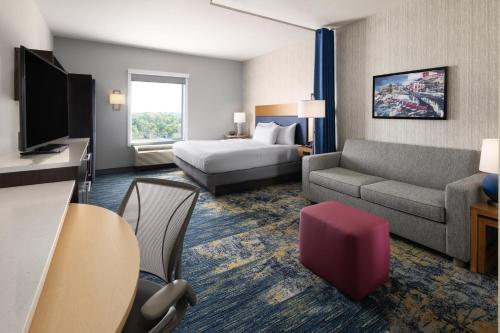 a hotel room with a bed and a couch at Home2 Suites by Hilton Greenville Downtown in Greenville