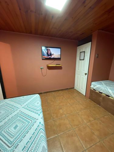 a bedroom with two beds and a tv on the wall at Residencial Don Santiago in Talca