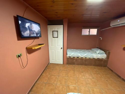 a room with a bed and a television on a wall at Residencial Don Santiago in Talca