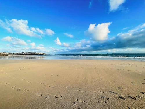 a beach with footprints in the sand and the ocean at MINSTER DREAMS - A perfect seaside retreat for couples near Porthminster beach in St Ives