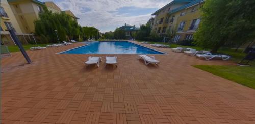 a swimming pool with lounge chairs next to a building at AVS Concept Cosmopolis in Ştefăneştii de Sus