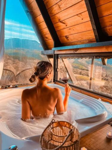 a woman in a hot tub with a glass of wine at Refúgio Mirante da Montanha in Alfredo Wagner