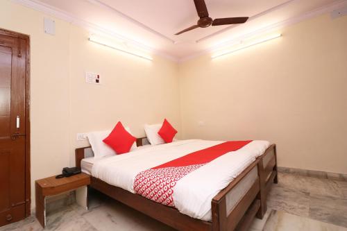 a bedroom with a bed with red pillows and a ceiling at Hotel O Midtown in Bhopal