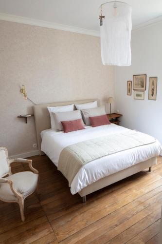 une chambre avec un grand lit blanc et une chaise dans l'établissement villa ma cayenne, à La Celle-sous-Gouzon