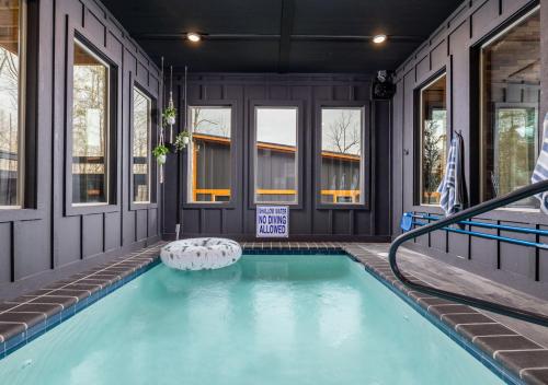 a swimming pool in a house with windows at Luxury Gatlinburg Cabin, Heated Pool, Theater, Hot Tub in Gatlinburg