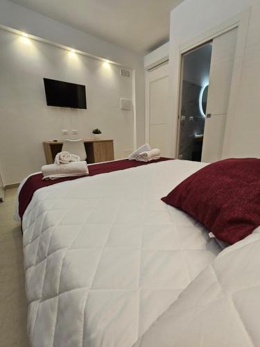 a bedroom with a large white bed with a tv on the wall at Aura B&B in Pachino