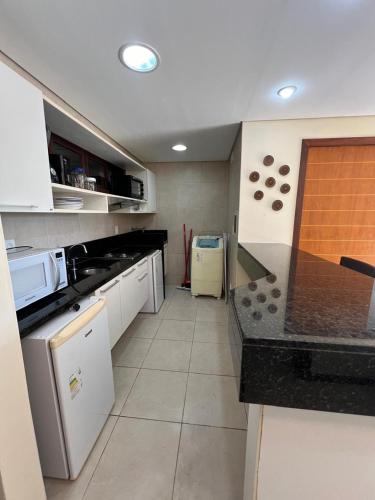 a kitchen with white cabinets and a black counter top at Kariri Beach Residence in Caucaia