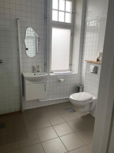 a white bathroom with a sink and a toilet at GrandStation Restaurant Room in Oskarshamn