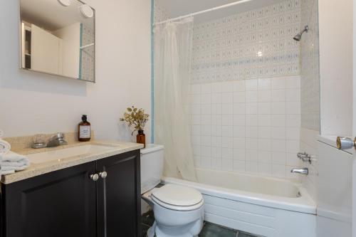 a bathroom with a toilet and a tub and a sink at Stunning 2B in Plateau Mont-Royal in Montréal