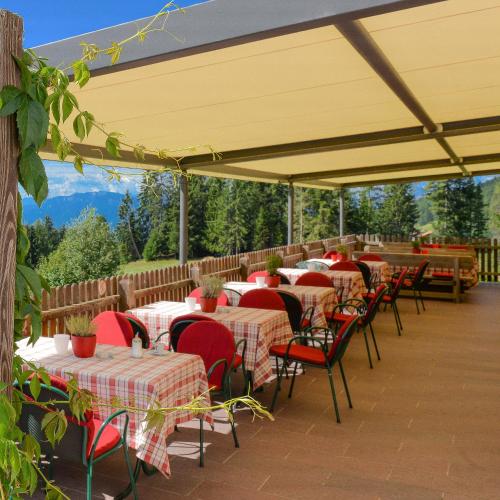 a row of tables and chairs under a yellow umbrella at Berghotel zum Zirm in Collalbo