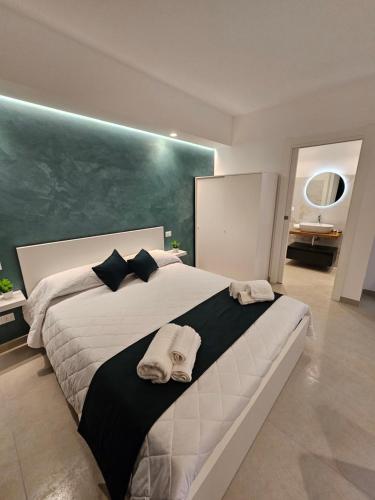 a bedroom with a large white bed with a green wall at Aura B&B in Pachino
