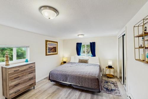 Un dormitorio con una cama y una cómoda y dos ventanas. en DnA Tiny beach House, en Reedsport