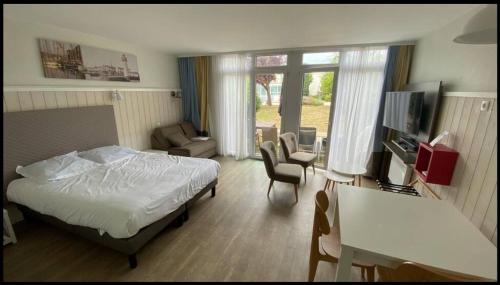 a hotel room with a bed and a living room at Studio Chateliers, piscine chauffée, spa et jardin à St Martin de Ré in Saint-Martin-de-Ré