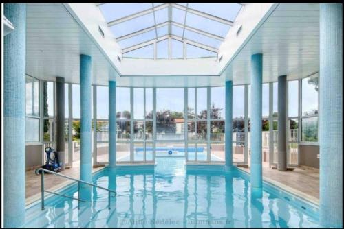 une grande piscine avec colonnes bleues et fenêtres dans l'établissement Studio Chateliers, piscine chauffée, spa et jardin à St Martin de Ré, à Saint-Martin-de-Ré