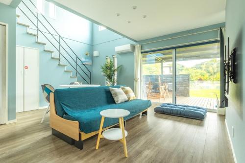 a living room with a blue couch and stairs at RD House in Katsuyama