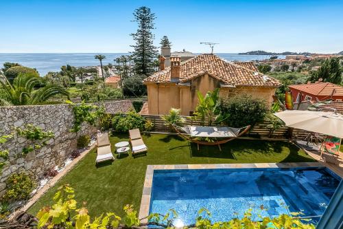 une cour arrière avec une piscine et une maison dans l'établissement Petit Paradis - Sea View, à Beaulieu-sur-Mer