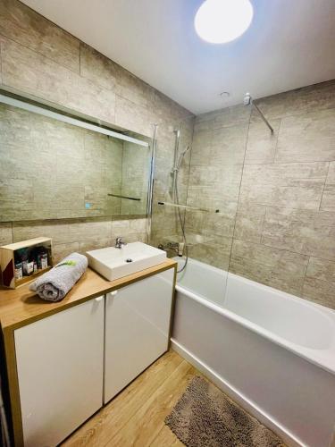 une salle de bain avec un lavabo et une baignoire dans l'établissement Studio avec piscine face à la mer, à Biarritz