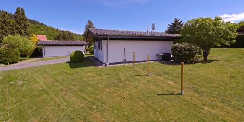 a house with a yard with poles in the grass at Ferienhaus Trüdi 2 - Gemütlicher freistehender Bungalow in Wolfshagen