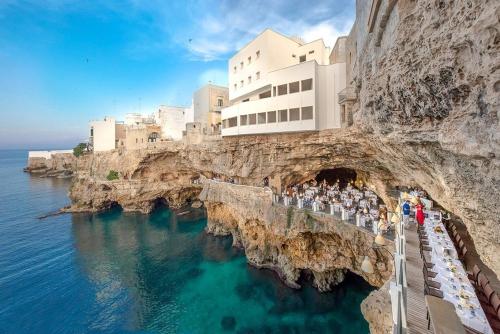 eine Gruppe von Menschen steht auf einer Klippe neben dem Wasser in der Unterkunft EL-MAR housea exclusive terrace, sea view in Polignano a Mare