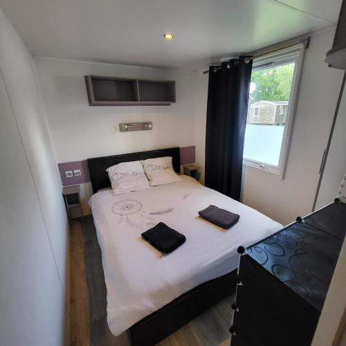 une chambre avec un lit avec deux serviettes dessus dans l'établissement MOBIL-HOME CONFORTABLE ET BIEN EQUIPE AVEC PISCINES ET LA PLAGE A PIED, à Fouesnant