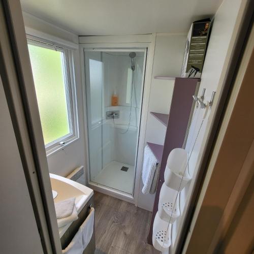une salle de bain avec douche et lavabo dans l'établissement MOBIL-HOME CONFORTABLE ET BIEN EQUIPE AVEC PISCINES ET LA PLAGE A PIED, à Fouesnant