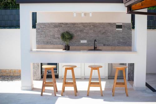 a kitchen with three wooden stools in front of a counter at Vacation villa Matic with 7 bedrooms in Sinj