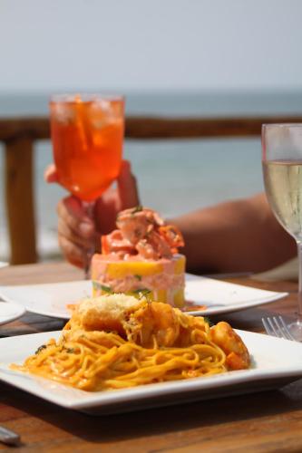 a plate of spaghetti on a table with a glass of wine at Baja Canoas Hotel in Canoas De Punta Sal